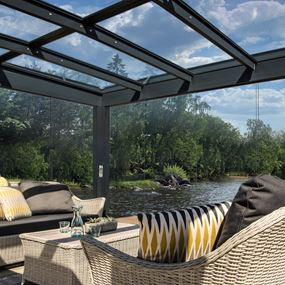 Vy inifrån lyxig glasveranda med glastak mot blå sommarhimmel