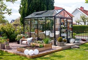 Ett mindre växthus i svart med plats för odling och umgänge.