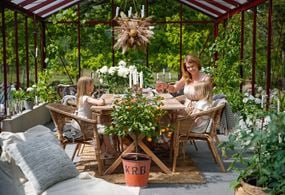 En mamma och hennes två döttrar fikar i sitt växthus en varm sommardag.