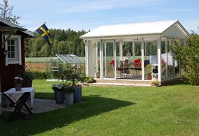 Miljöbild på fristående uterum med sadeltak, helt i vitt