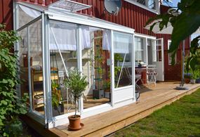 Miljöbild på växhuset Midi, med vitlackerat aluminium, monterat mot en vägg.