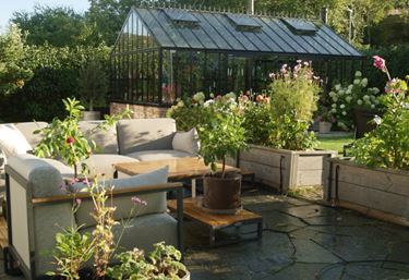 Loungemöbler på altan med växthus i bakgrunden