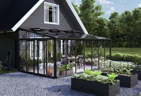 Miljöbild på växthuset Green room Lean To, i svartlackerad aluminium. Byggd mot vägg.